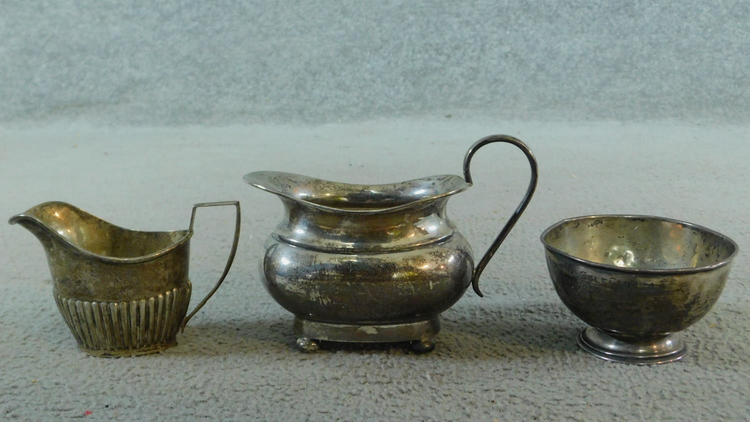 Three sterling silver items. Including an Art Deco milk jug on four button feet, hallmarked: EV