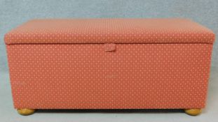 An upholstered ottoman with fully lined interior on squat bun feet. H.49 W.109 D.48cm
