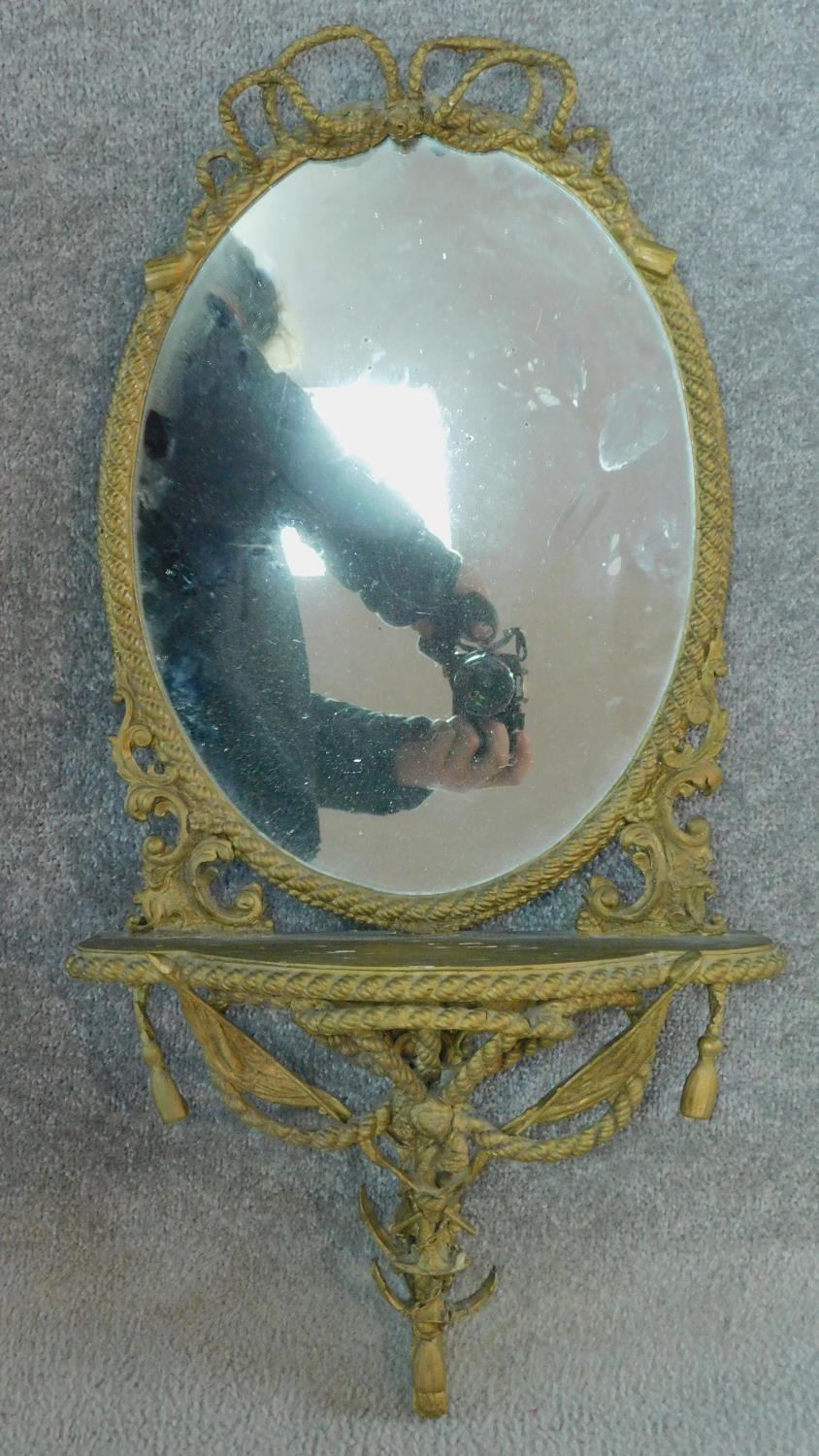 A late 19th century gesso framed wall mirror with shaped shelf and ribbon and swag decoration.