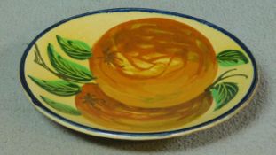 A large vintage glazed ceramic footed charger hand painted with two large orange fruits and foliage.