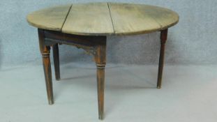 An antique country oak single drop flap table with gateleg action and fitted frieze drawer on turned