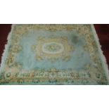 A large Chinese woollen carpet with central floral medallion on pale blue ground and floral borders.