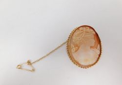 A 9 ct gold cameo brooch with yellow metal safety chain. The cameo is carved with a female profile