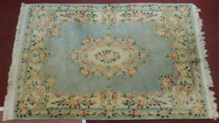 A Chinese woollen carpet with central floral medallion on pale blue ground and floral borders.