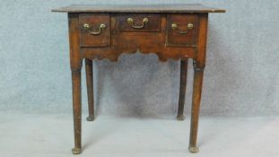 A Georgian country oak lowboy fitted with three frieze drawers raised on tapering circular section