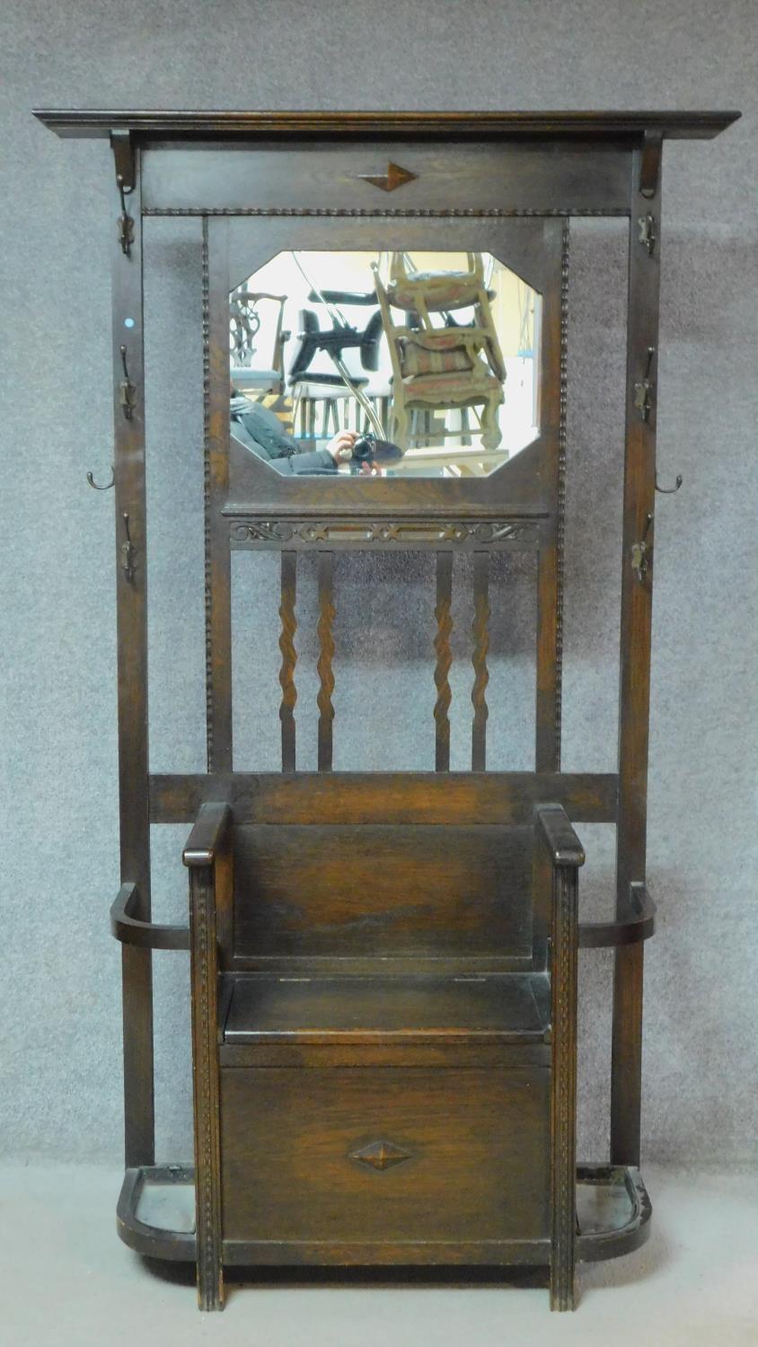 An antique style oak hallstand fitted with mirror above box seat with lift up top enclosing shoe