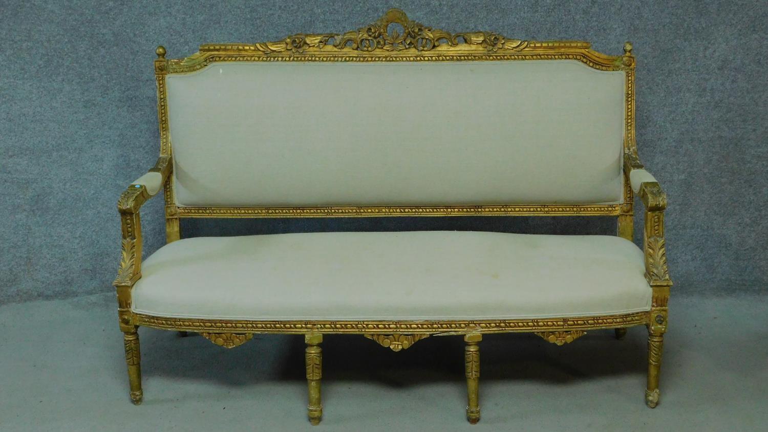 A Louis XVI style carved giltwood sofa with cream upholstery raised on turned tapering supports. H.