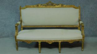 A Louis XVI style carved giltwood sofa with cream upholstery raised on turned tapering supports. H.
