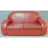 An Art Deco style two seater sofa in burgundy leather upholstery together with the matching stool.