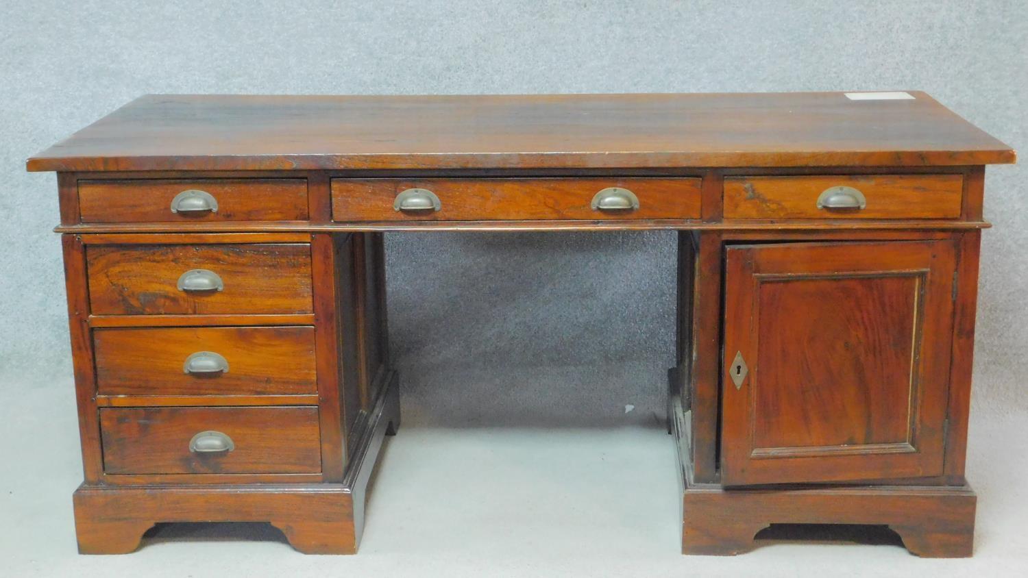 An Eastern teak three part pedestal desk fitted with a cupboard and drawers on bracket feet. H.78