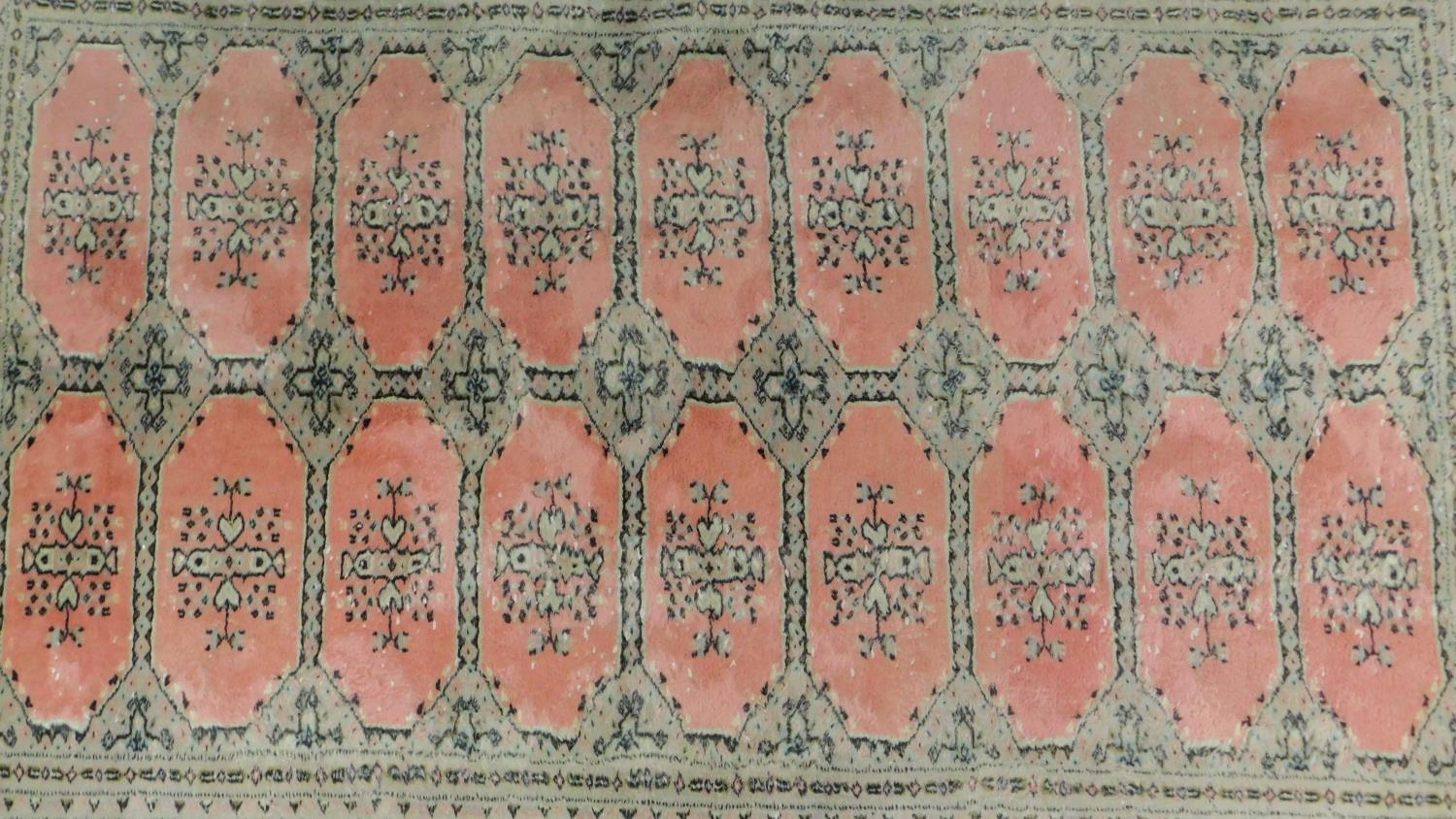 A woollen Bokhara style carpet with repeating lozenge motifs on rouge ground contained within - Image 2 of 4