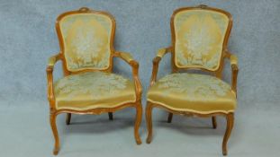 A pair of Louis XV style carved walnut armchairs in gold floral design moquette cut upholstery on