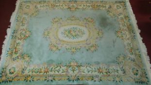 A large Chinese woollen carpet with central floral medallion on pale blue ground and floral borders.