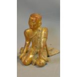 An early 20th century South East Asian lacquered carved gilt wood seated statue of the Monk