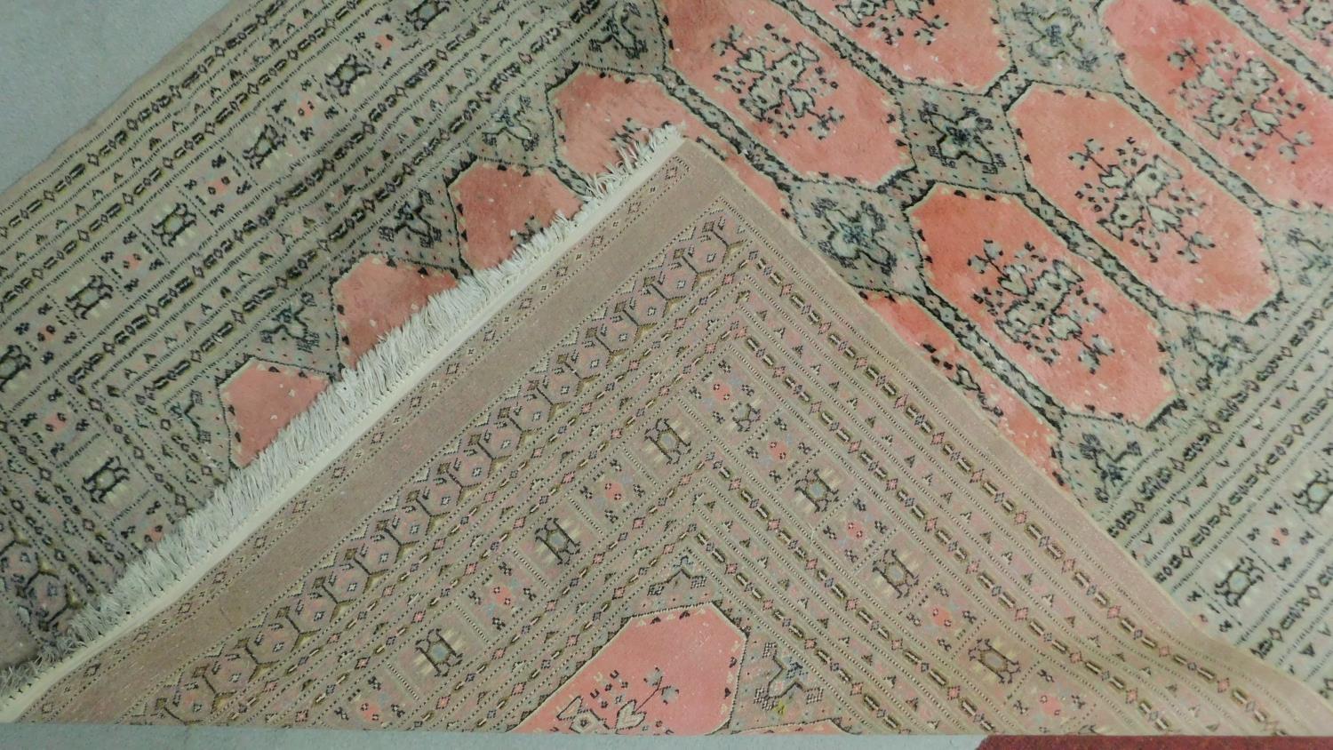 A woollen Bokhara style carpet with repeating lozenge motifs on rouge ground contained within - Image 4 of 4