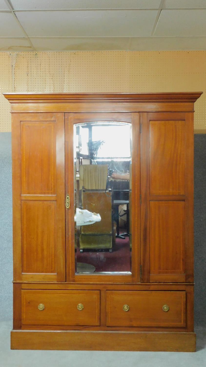 An early 20th century mahogany and satinwood inlaid wardrobe with central panel door fitted with