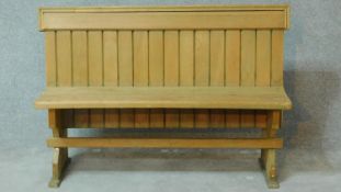 A vintage light oak panelled back settle on trestle supports. H.83 W.126 D.45cm