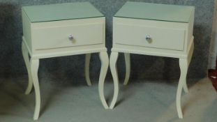 A pair of contemporary white lacquered bedside cabinets with plate glass tops above frieze drawers