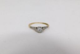 A 18 carat yellow gold and platinum flanked solitaire ring. Set to centre with a round brilliant cut
