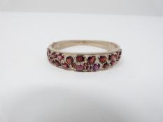 Bespoke Garnet and silver bangle. Set with twenty mixed cut garnets in open back claw settings.