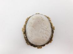 A Victorian yellow metal cameo brooch with an engraved scalloped border and carved shell cameo