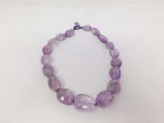 A statement faceted amethyst pebble necklace with a silk chord loop clasp. Composed of graduated