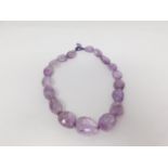 A statement faceted amethyst pebble necklace with a silk chord loop clasp. Composed of graduated