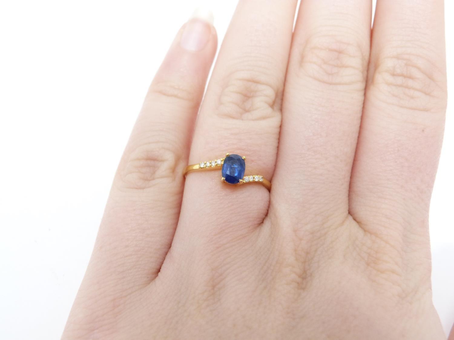 A heated Ceylon sapphire and diamond flanked solitaire 14 carat gold ring. Set with a central oval - Image 6 of 7