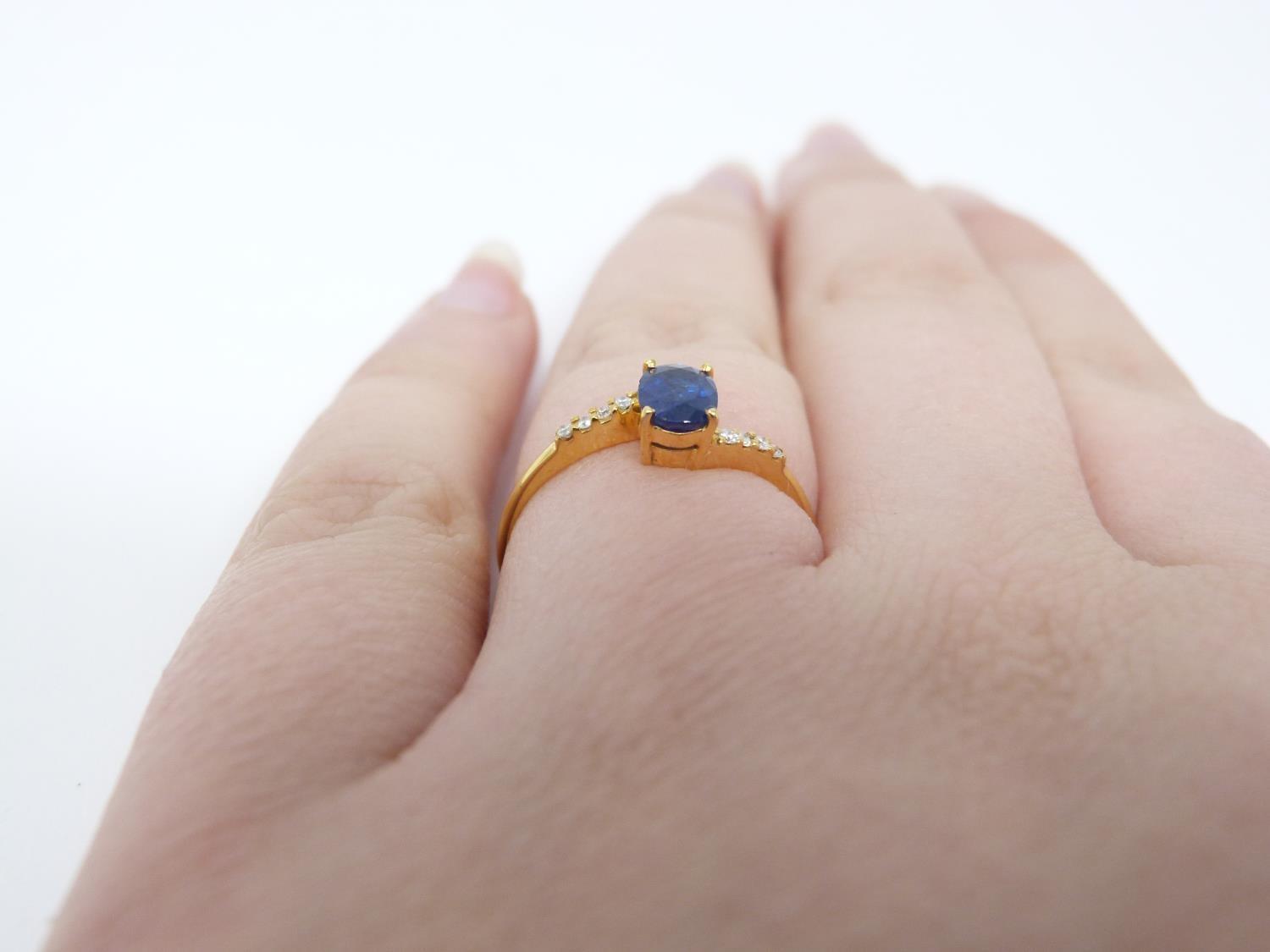 A heated Ceylon sapphire and diamond flanked solitaire 14 carat gold ring. Set with a central oval - Image 5 of 7