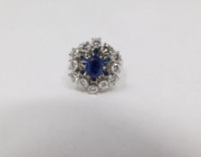 A vintage 14 carat white gold sapphire and diamond cluster ring. Set to center with an oval mixed