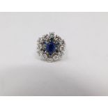 A vintage 14 carat white gold sapphire and diamond cluster ring. Set to center with an oval mixed