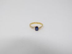 A heated Ceylon sapphire and diamond flanked solitaire 14 carat gold ring. Set with a central oval