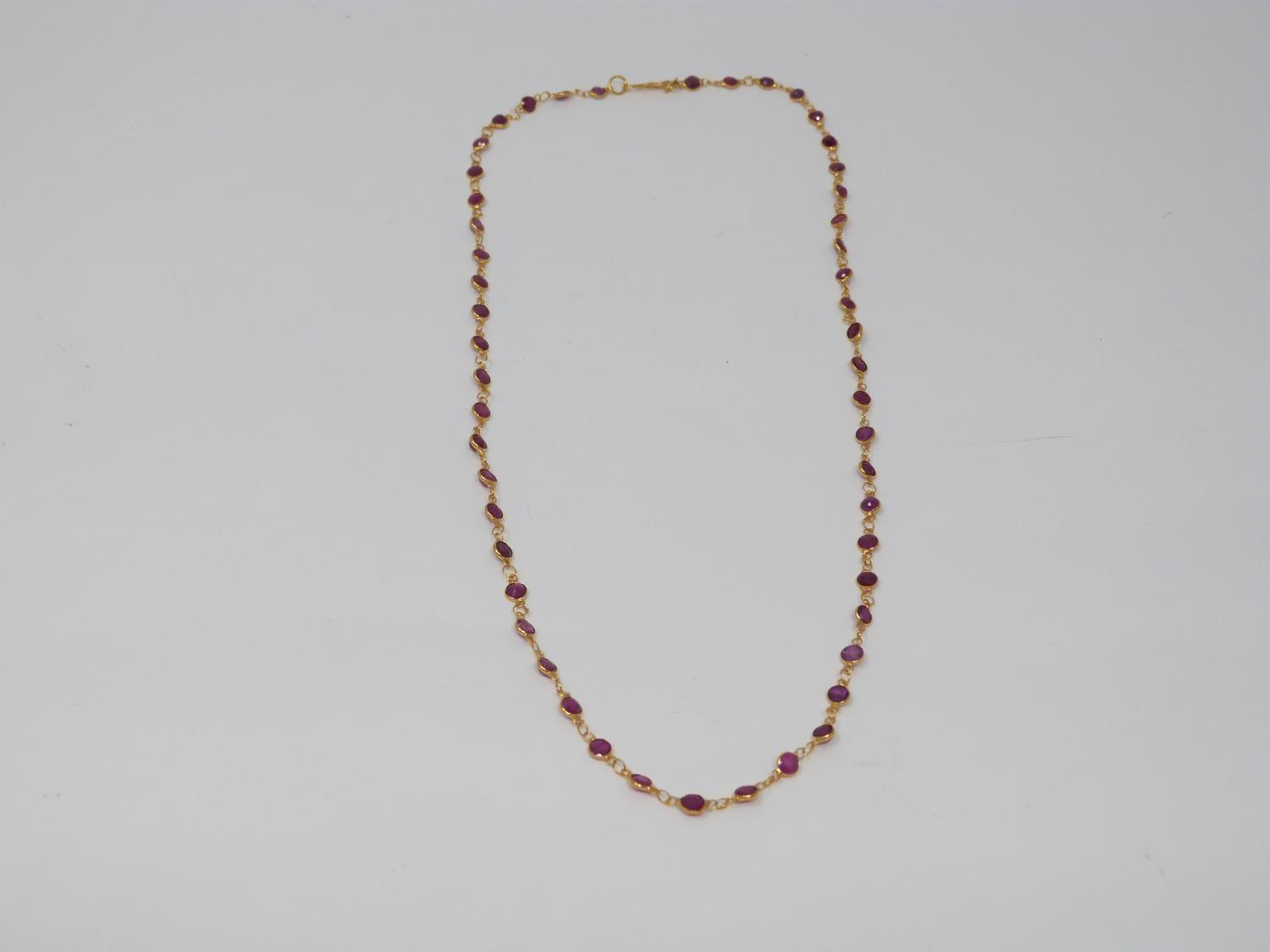 A bespoke yellow metal (tested 14 carat yellow gold) and ruby chain necklace. Set with fifty one
