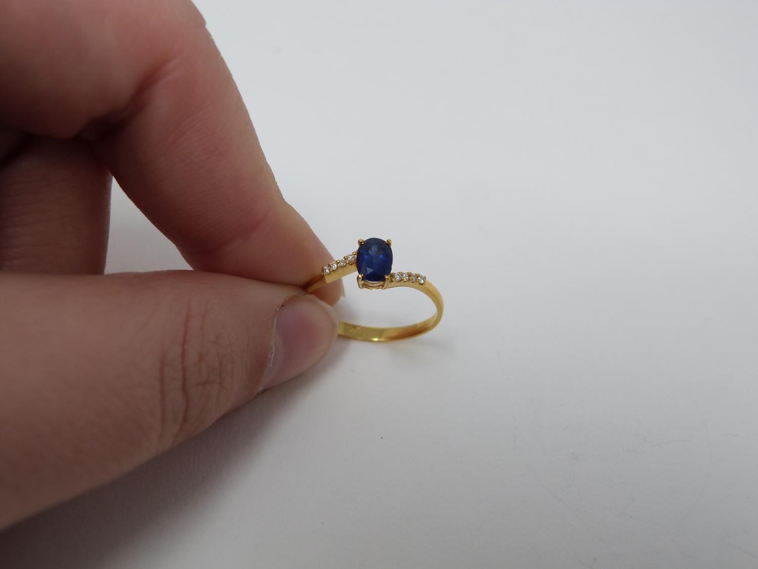 A heated Ceylon sapphire and diamond flanked solitaire 14 carat gold ring. Set with a central oval - Image 4 of 7