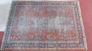 A Persian carpet with allover scrolling foliate decoration on a burgundy ground contained within