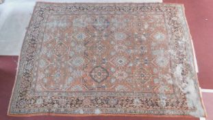 A large Persian carpet with allover stylised floral motifs on a rouge ground within floral multi