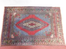 A Mallayer style rug with central lozenge medallion on blue ground within stylised floral multi