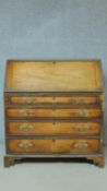 A Georgian mahogany bureau with fall front revealing fitted interior above four graduating oak