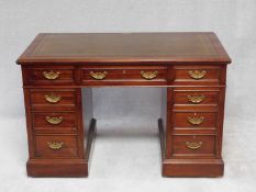 An early 20th century mahogany pedestal desk with inset tooled leather top above an arrangement of