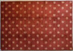 A silk and wool rug with repeating geometric flowerhead design on a burgundy field. L.237x170cm