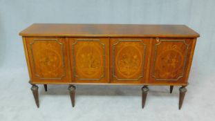 A Continental flame mahogany four door sideboard with floral inlaid panels on fluted tapering