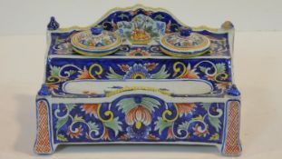 A Continental faience inkstand with twin inkwells and pen tray and allover polychrome foliate