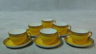 A set of six vintage bright yellow and black china tea cups and saucers with a relief stylised