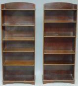 A pair of Edwardian mahogany tall open bookcases with arched backs and adjustable shelves on