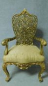 A Burmese carved teak throne chair with intricately carved floral back in lemon upholstery. Later