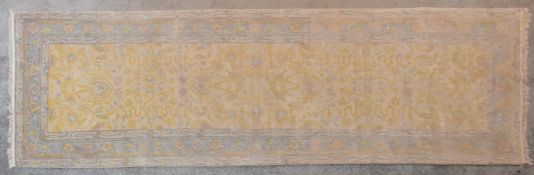 An Indian Agra runner with repeating floral motifs on a cream ground within a foliate border. L.