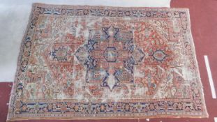 A Persian carpet with central pendant medallion and spandrels on burgundy ground within foliate