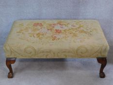 A large tapestry upholstered footstool on beech ball and claw carved cabriole supports. H.34 W.100