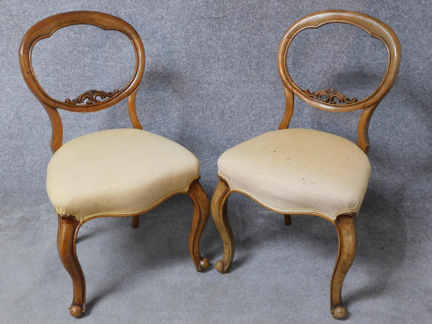 A pair of Victorian walnut balloon back dining chairs in damsk upholstery on cabriole supports. H.