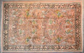 A Kashmir silk rug depicting a hunting scene on a blush ground contained within a stylised border.